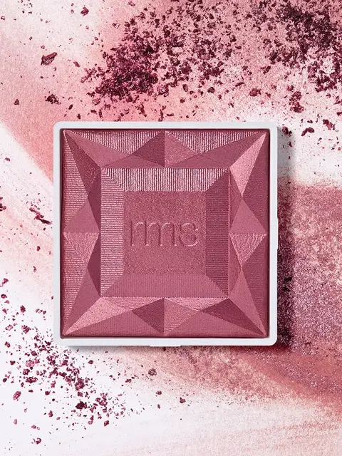 Pink geometric blush compact with "rms" embossed, surrounded by scattered blush powder.