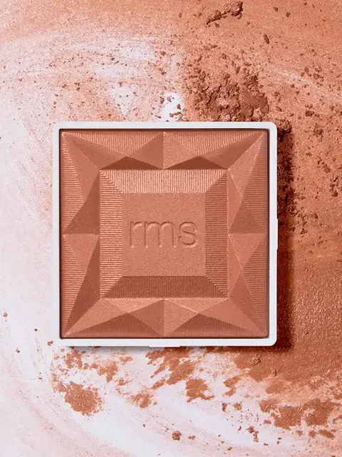 Square bronzer compact with "rms" embossed, surrounded by loose powder.