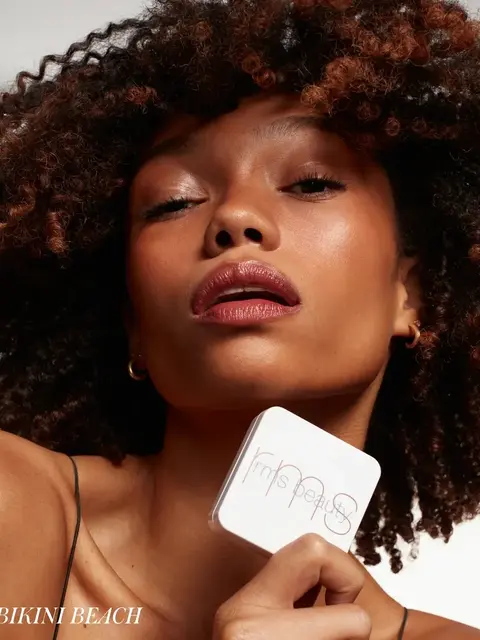Person holding rms beauty compact, text "BIKINI BEACH" in corner.