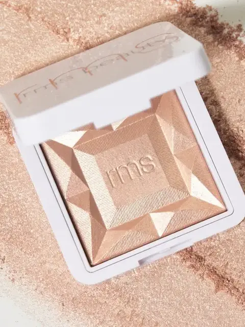Open compact with embossed "rms" on a textured, shimmering powder surface.