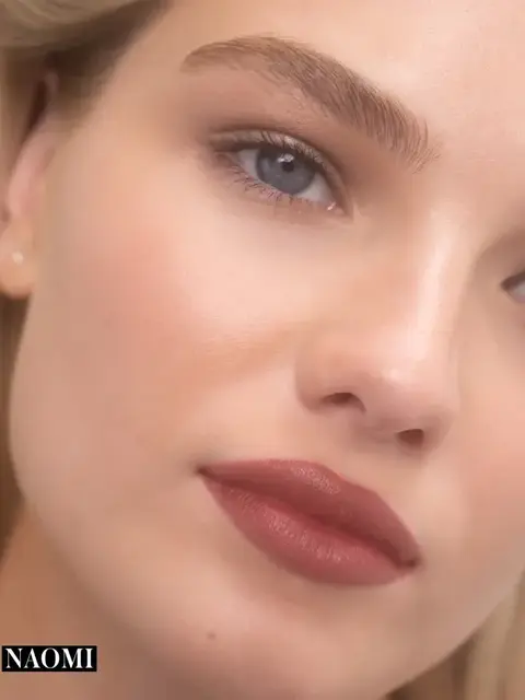 Close-up of a person with smooth skin, red lipstick, and text "NAOMI" in the corner.