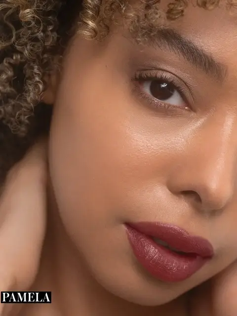 Close-up of a person with curly hair and red lipstick. Text: "PAMELA" in the corner.