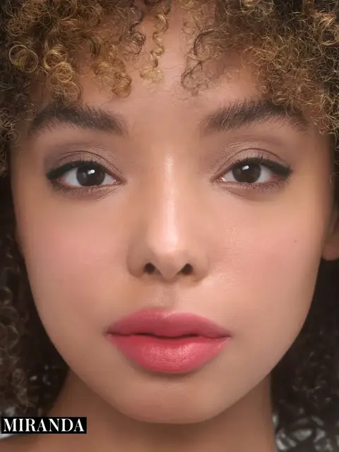 Close-up of a person with curly hair and pink lipstick. Text: "MIRANDA".