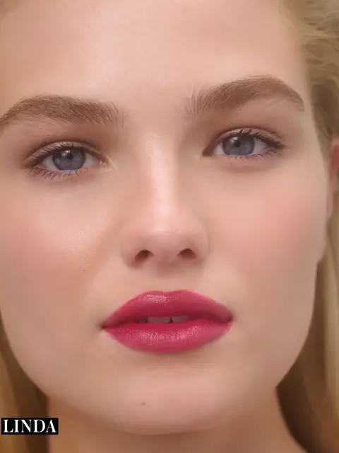 Close-up of a person with pink lipstick and blue eyes. Text: "LINDA" in the corner.