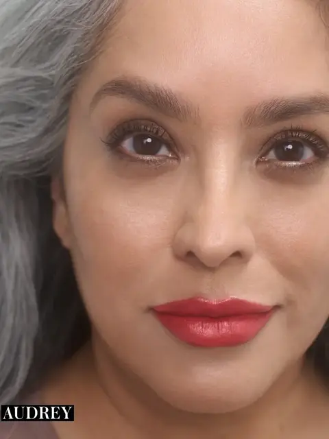 Woman with grey hair and red lipstick, text "AUDREY" in corner.