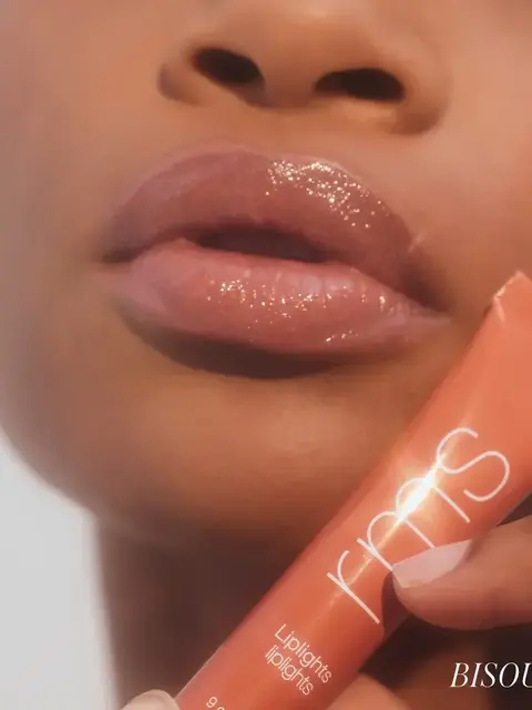 Close-up of glossy lips with RMS lip gloss tube. Text: "Liplights" and "BISOU".