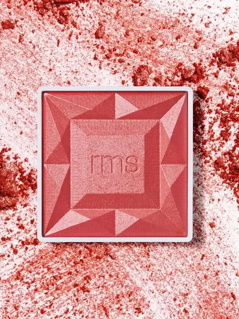 Red blush compact with "rms" logo, surrounded by scattered blush powder.