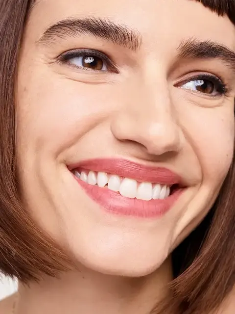 Smiling person with short brown hair and visible teeth.