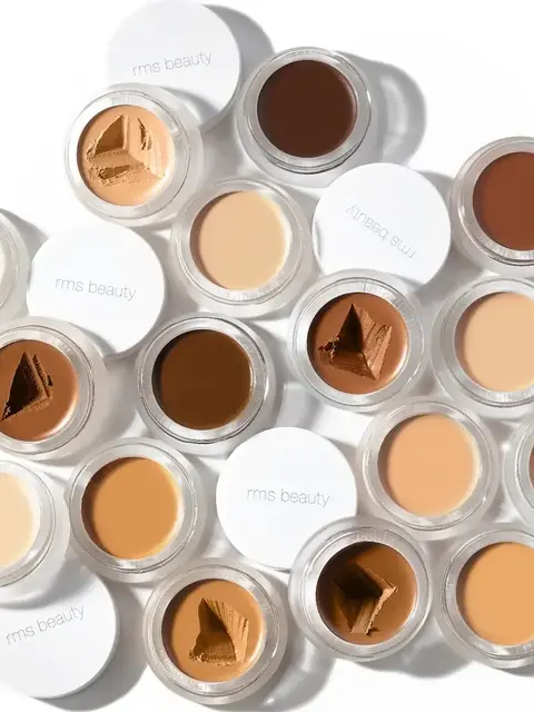 Assorted RMS Beauty concealer pots in various skin tones.
