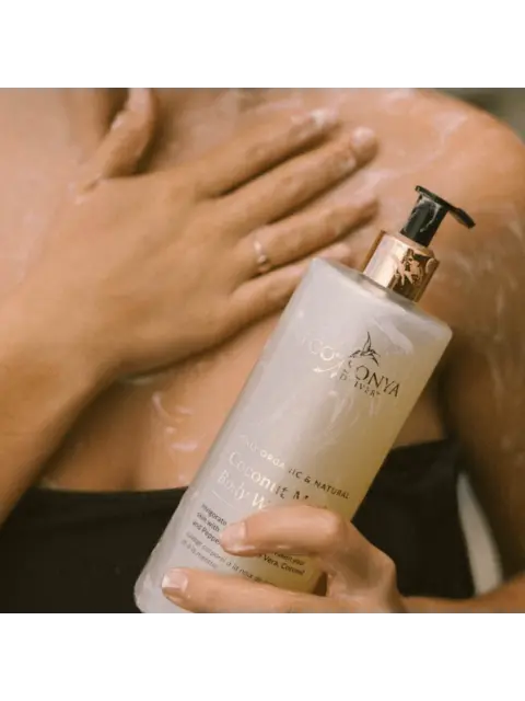 Person applying coconut body wash to shoulder.