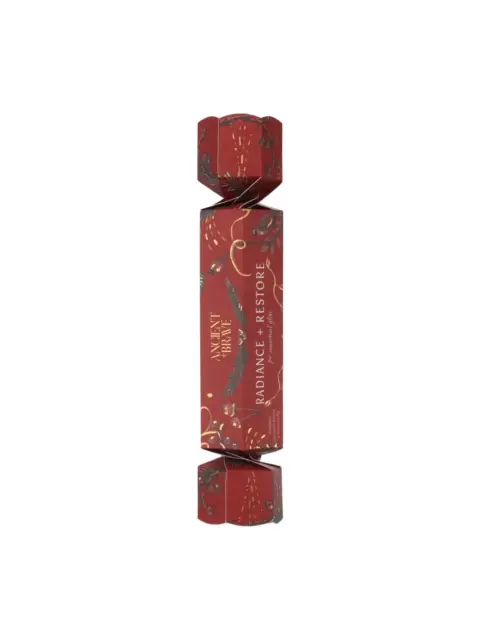 Red cracker with "Radiance + Restore" text and festive design.