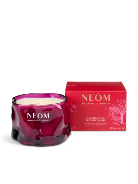 Purple NEOM candle with red box, labelled "Christmas Wish Scented Candle".