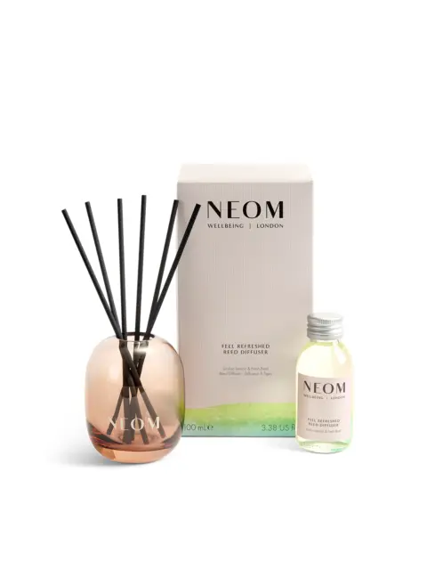 Neom reed diffuser set with box, glass bottle, and reeds. Text: "Feel Refreshed".