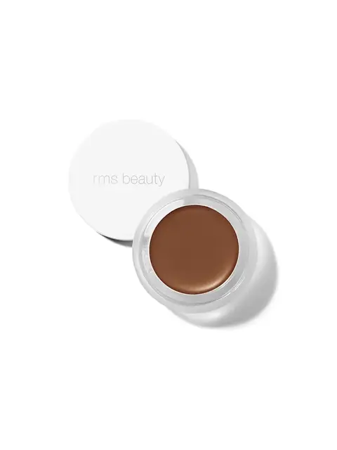 Open jar of brown cream makeup with "rms beauty" on the lid.