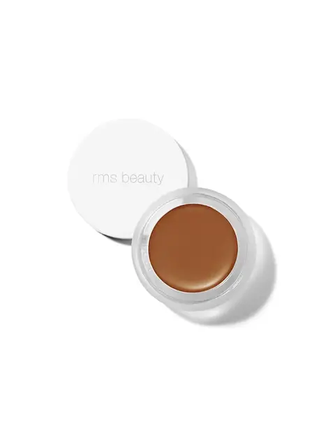 Open jar of brown cream makeup with "rms beauty" on the lid.