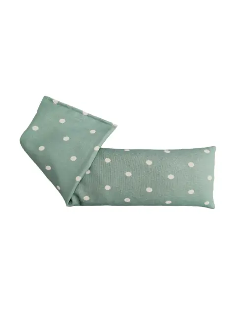 Green polka dot fabric eye pillow, folded at one end.