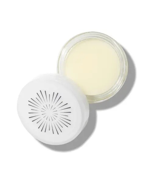Open jar of cream with a white lid featuring a sunburst design.
