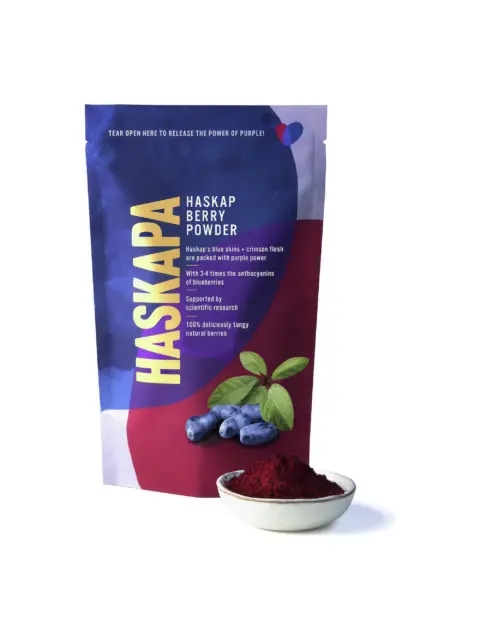 Haskapa berry powder pouch with bowl of red powder and fresh berries.