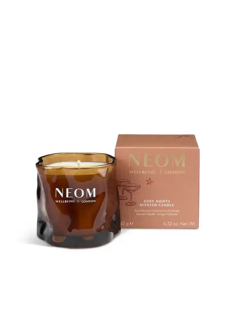 Brown glass candle with "NEOM Wellbeing London" text, next to a matching box labelled "Cosy Nights".