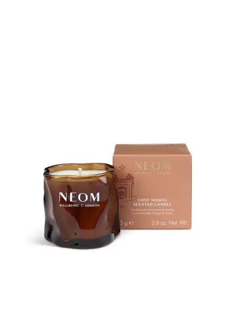 Brown glass candle with "NEOM Wellbeing London" text, next to a matching box.