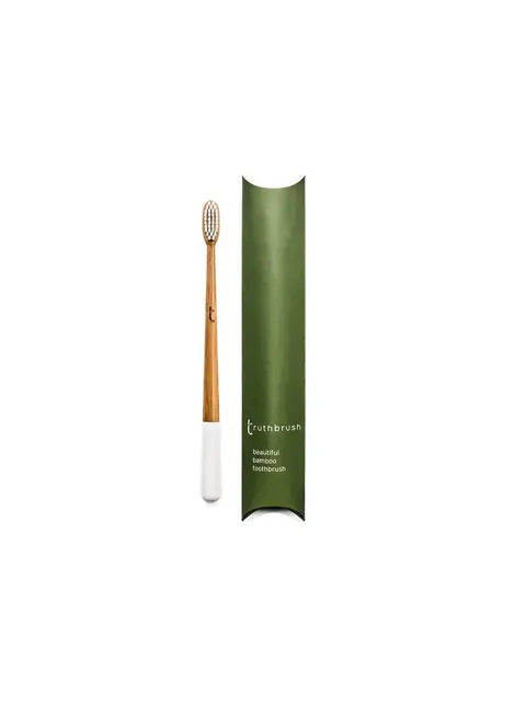 Bamboo toothbrush with white handle next to green packaging labelled "truthbrush".