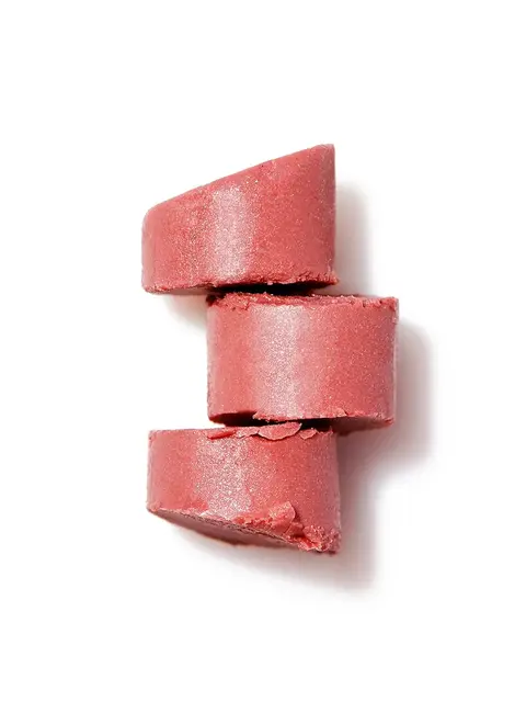 Three stacked pink solid shampoo bars on a white background.