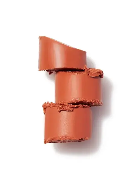 Three stacked slices of terracotta lipstick on a white background.