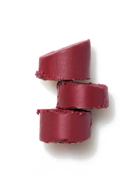 Three stacked slices of deep red lipstick on a white background.