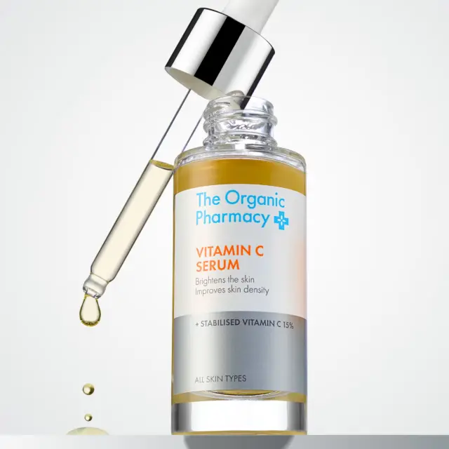 The Organic Pharmacy Vitamin C Serum with dropper and liquid droplet.