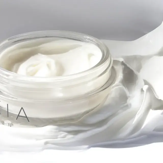 Open jar of white cream on a smooth surface.