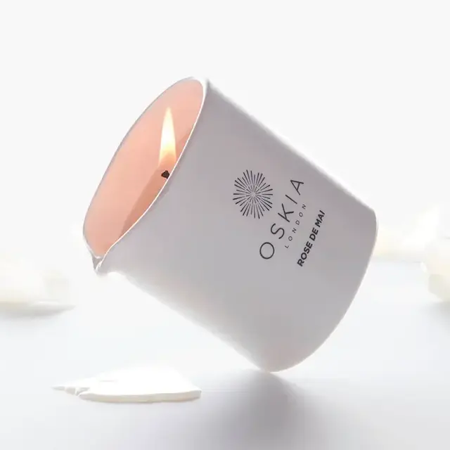 White candle labelled "OSKIA London Rose de Mai" with petals around.