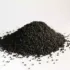 Pile of black seeds scattered on a white surface.