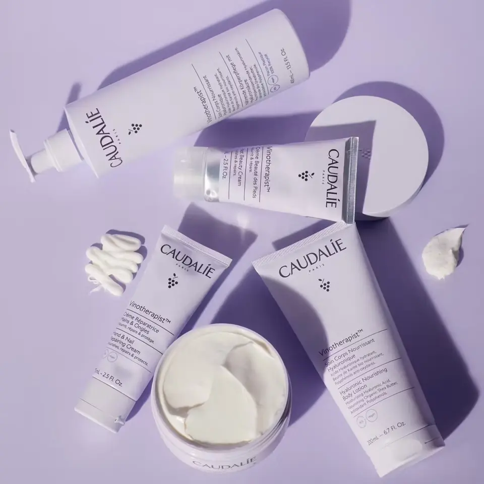 Caudalie skincare products on a purple surface, including creams and lotions.