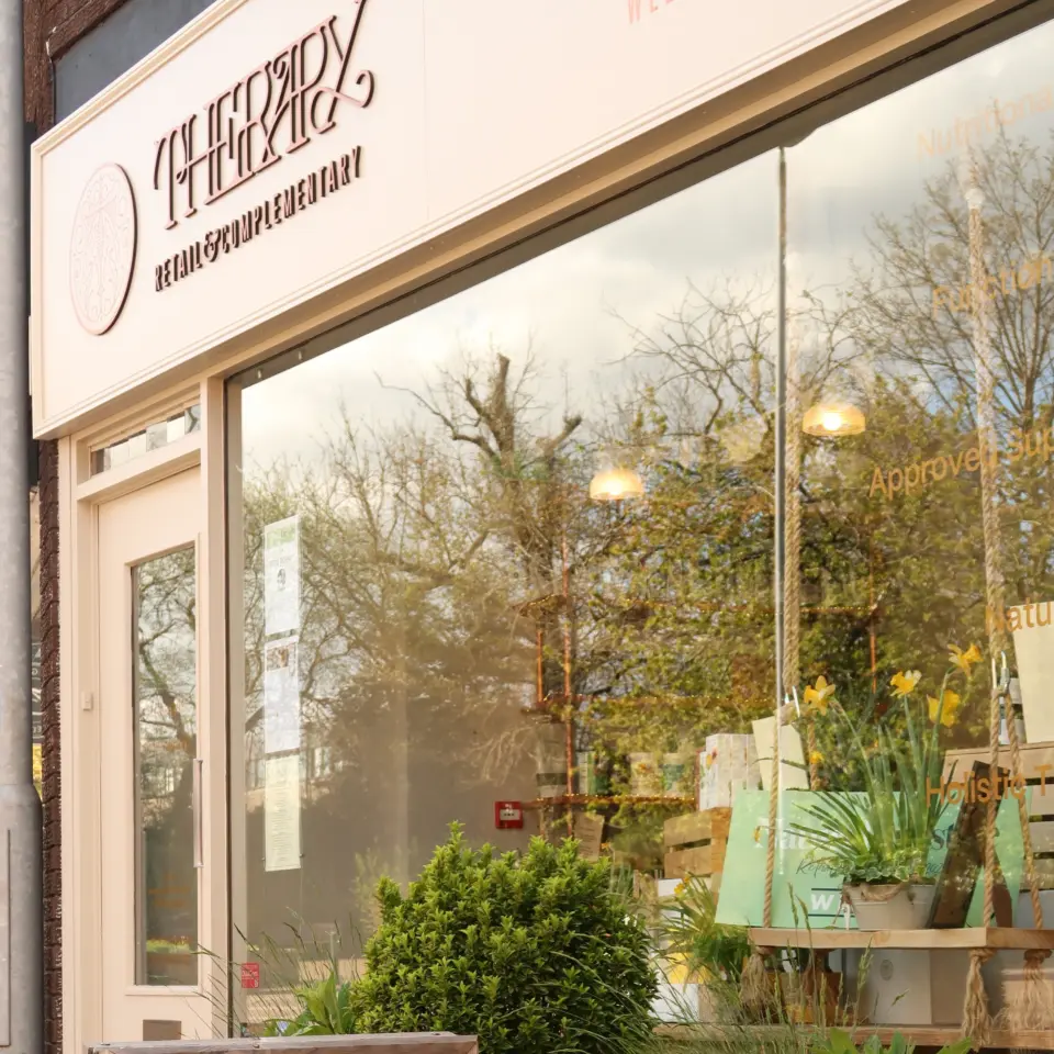 Shopfront with "Therapy" sign, plants, and a yellow sign reading "Natural Wellness, Natural Beauty".