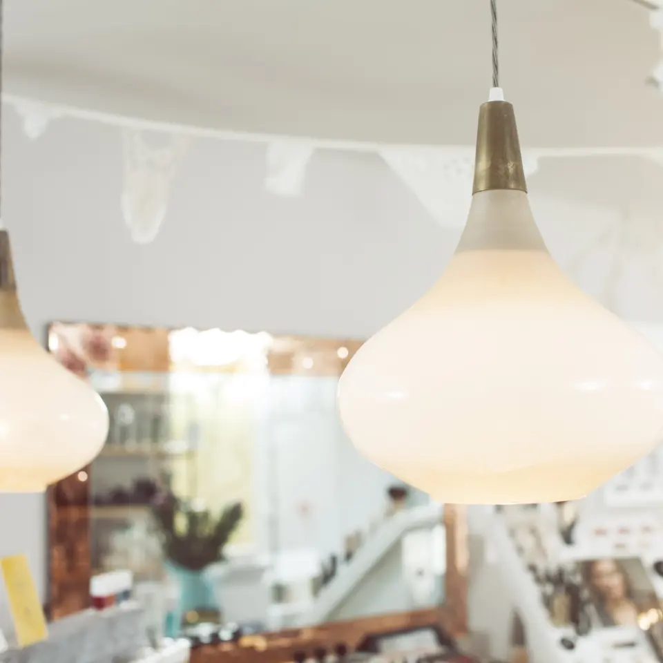 Two pendant lights in a skincare shop with shelves and a mirror in the background.