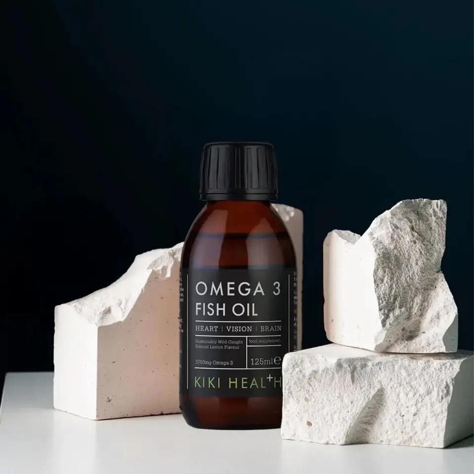 Omega 3 Fish Oil bottle with white rocks, dark background.