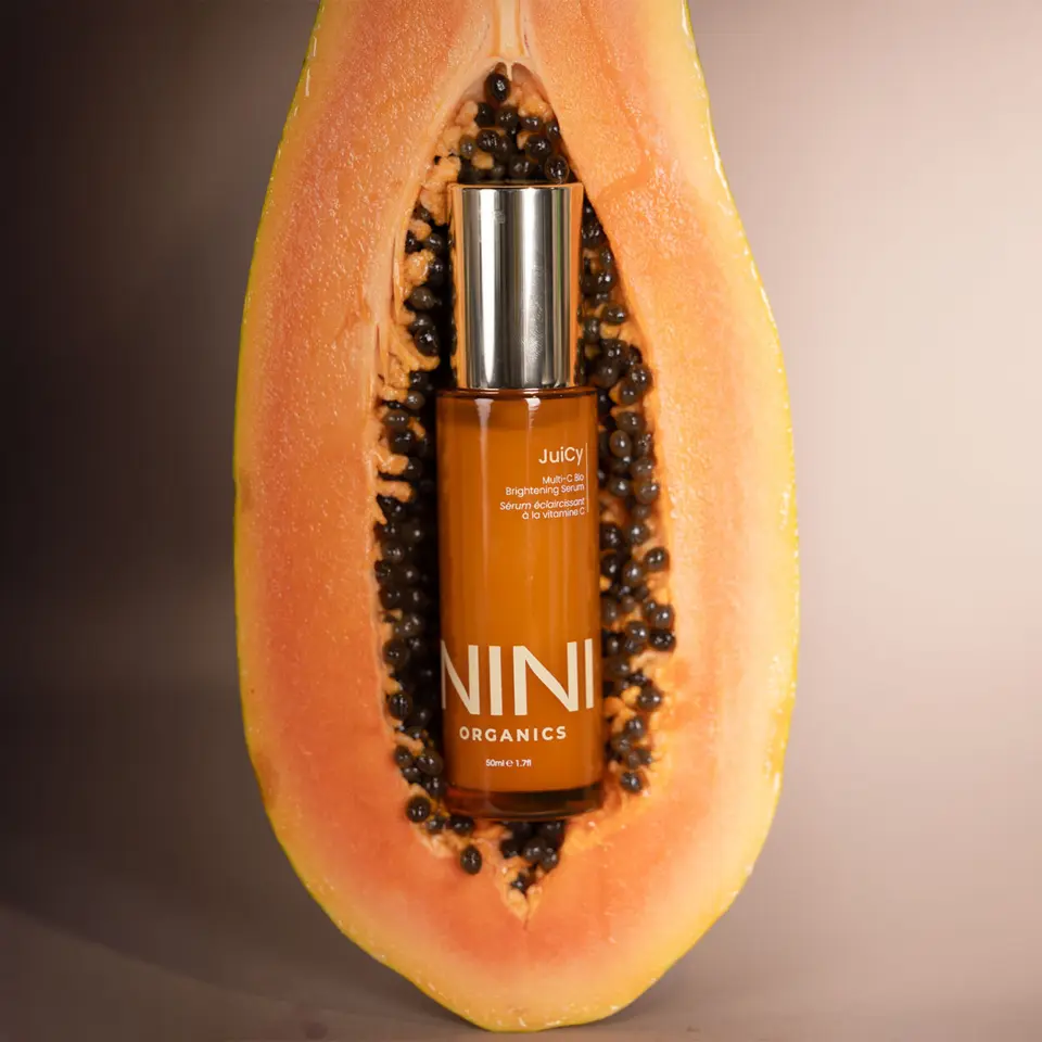NINI Organics serum bottle inside a halved papaya.