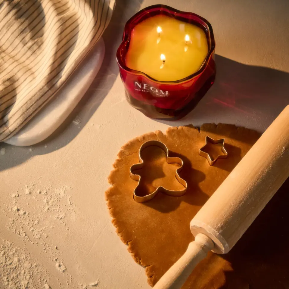 Red candle labelled "NEOM", dough with cutters, rolling pin, and striped cloth.
