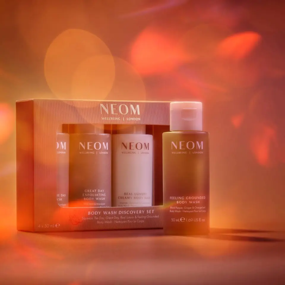 NEOM Body Wash Discovery Set with three bottles against a warm, blurred background.
