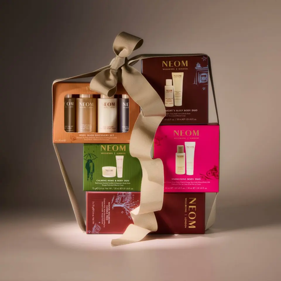 Gift set with NEOM skincare products, wrapped with a large beige ribbon.