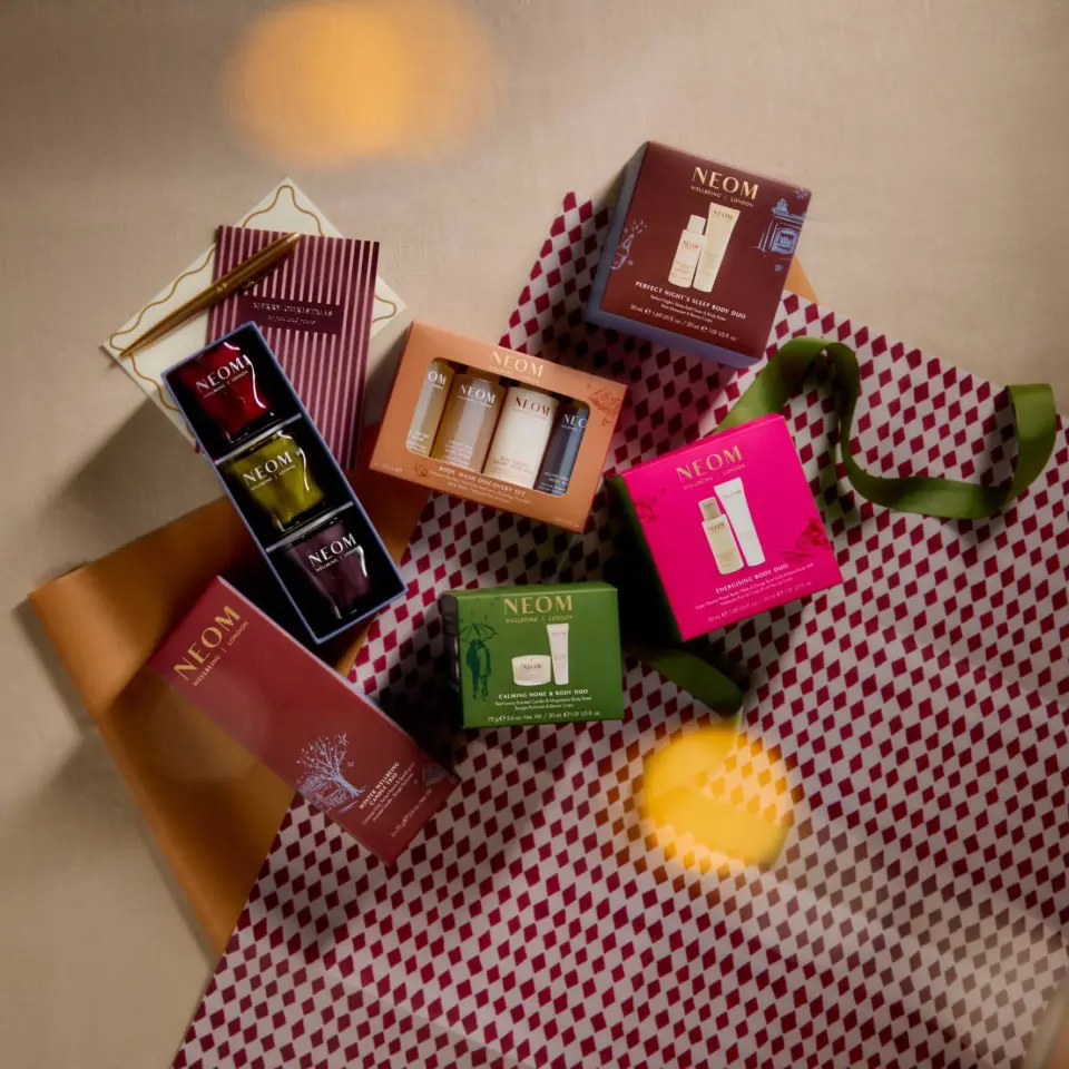 Neom skincare gift sets on patterned wrapping paper with ribbon.