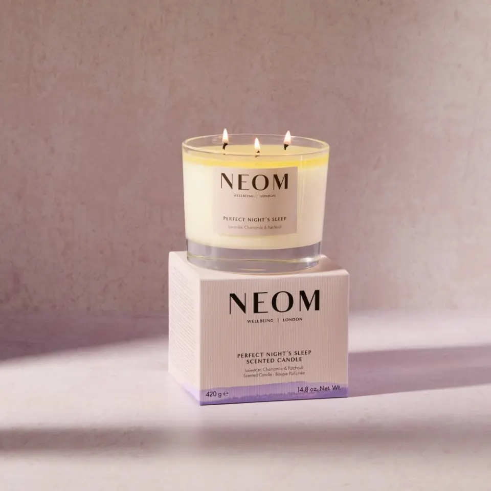 NEOM Perfect Night's Sleep scented candle on a box, lit with three wicks.