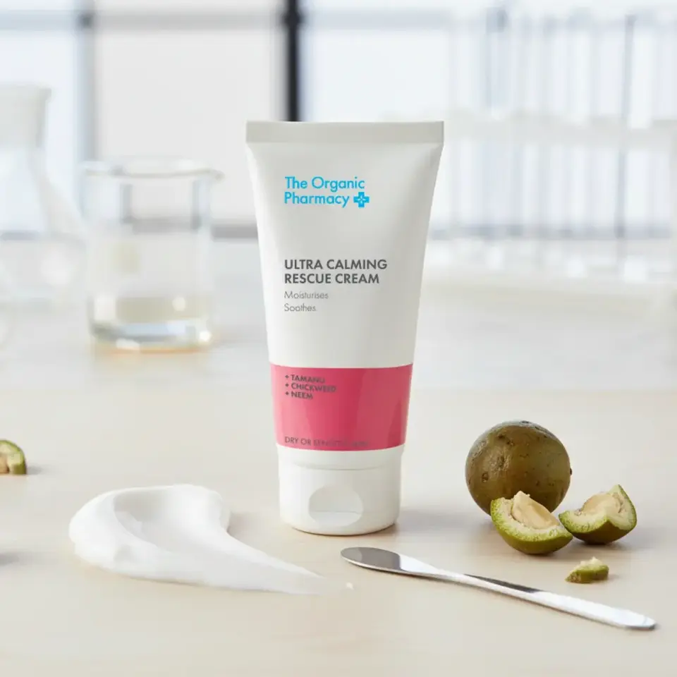 Tube of Ultra Calming Rescue Cream on table with sliced fruit and cream smear.
