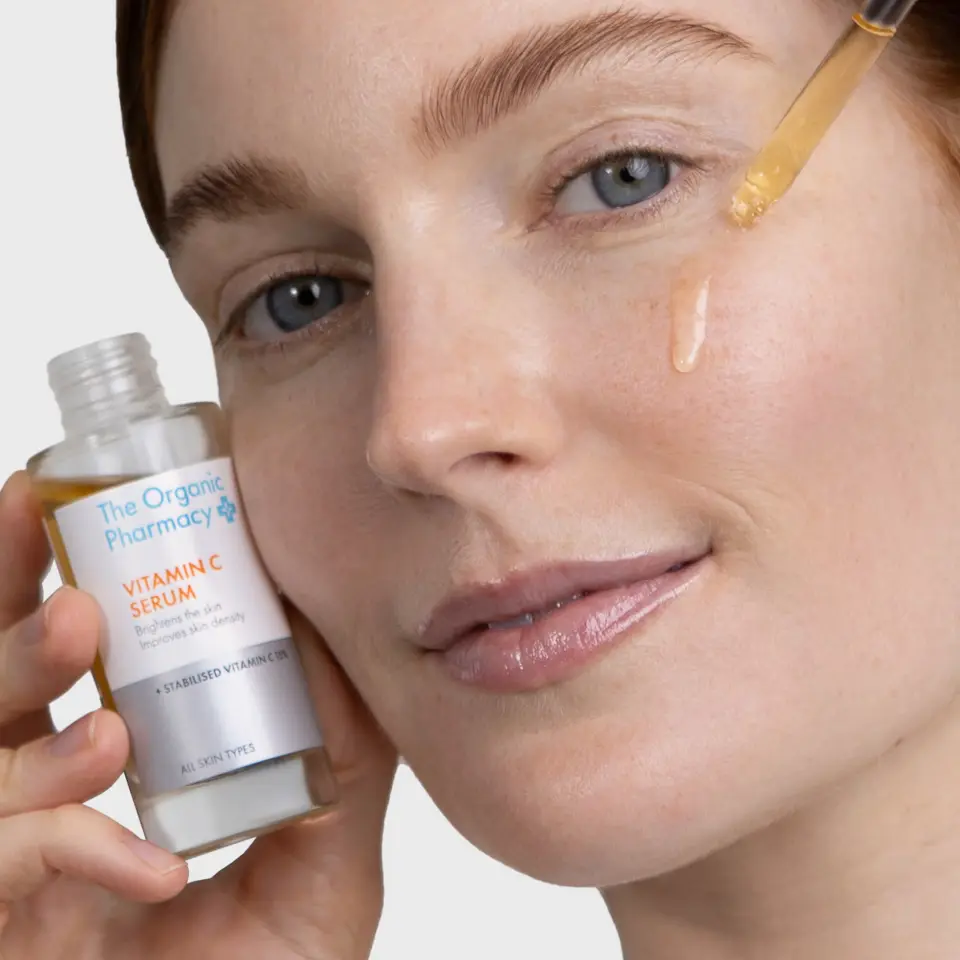 Woman applying The Organic Pharmacy Vitamin C Serum to her face.