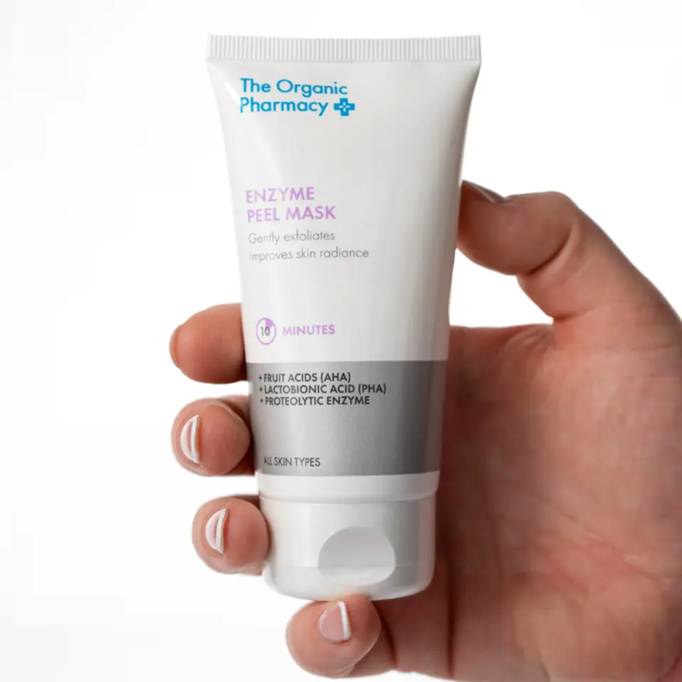 Hand holding The Organic Pharmacy Enzyme Peel Mask tube.