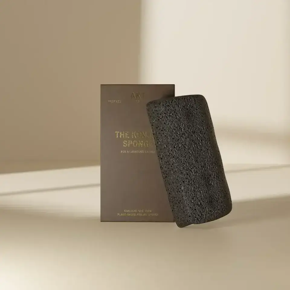 Black konjac sponge with brown packaging on a beige background.