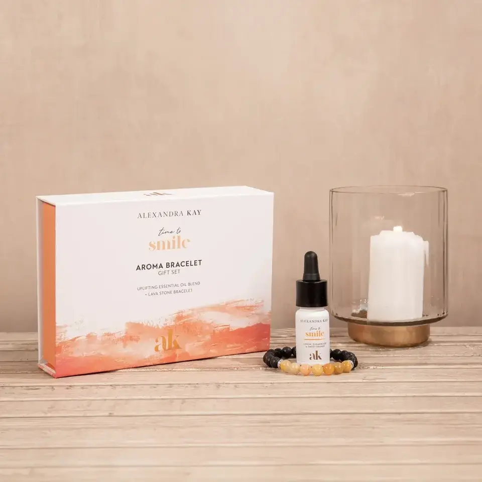 Aroma bracelet gift set with essential oil, bracelet, and candle on wooden surface.