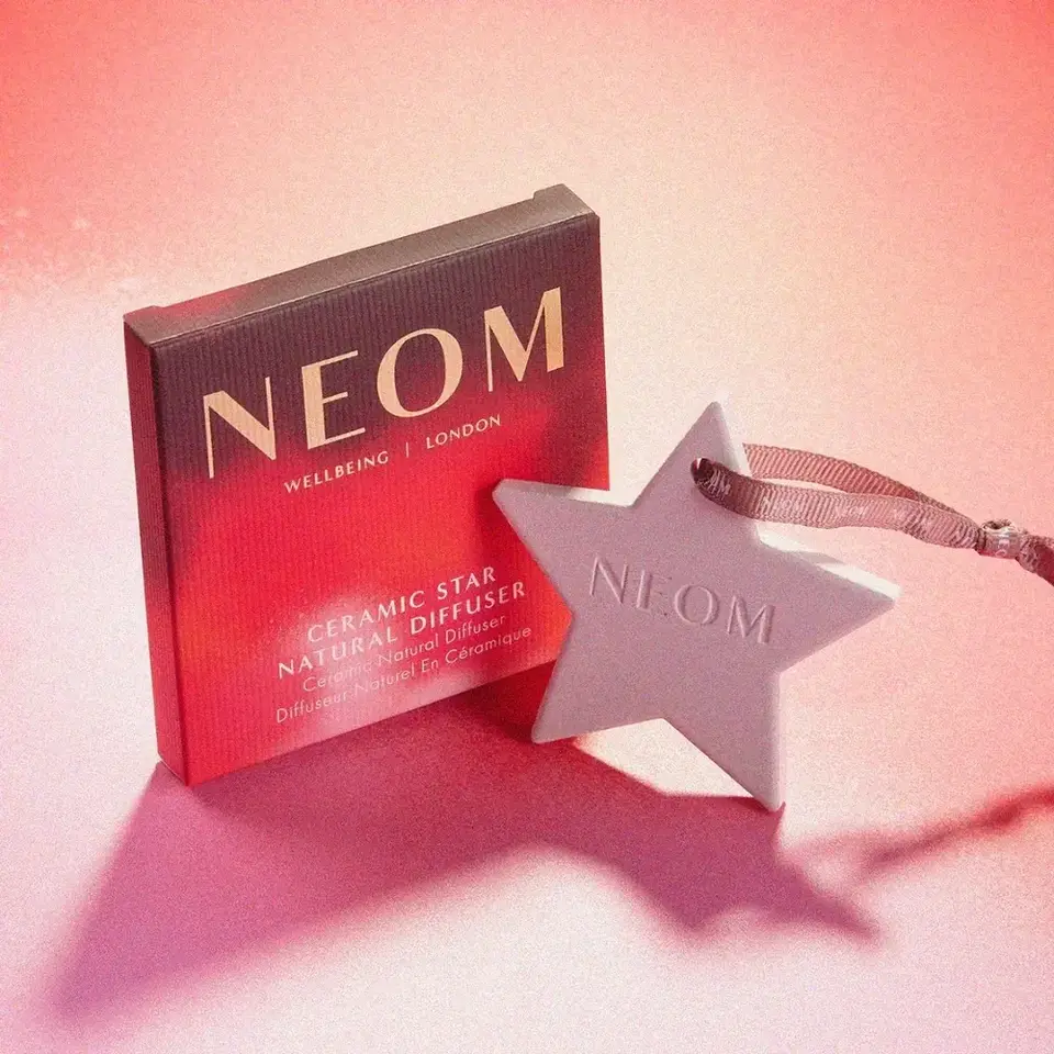NEOM ceramic star natural diffuser with ribbon on pink background.