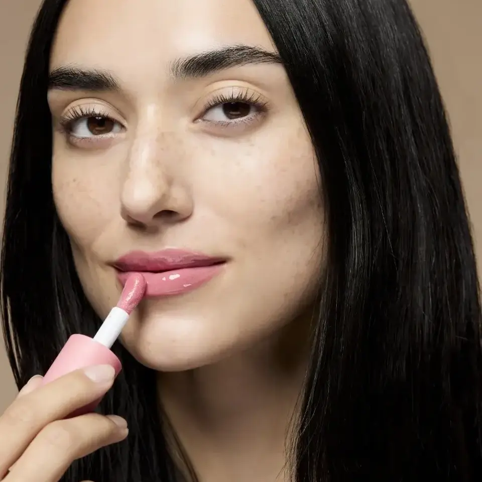 Woman applying pink lip gloss, text "KAROLINA" in corner.