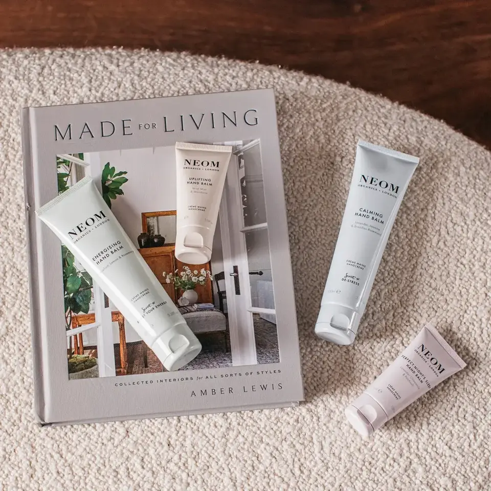 Neom hand balms on a book titled "Made for Living" by Amber Lewis on a textured surface.